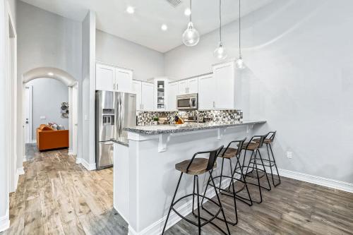 a kitchen with white cabinets and bar stools at 114 Mediterranean Way in Indian Harbour Beach