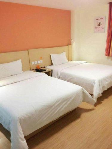 two beds in a hotel room with white sheets at 7 Days Inn Jinan Changqing Jingshi West Road Center in Jinan