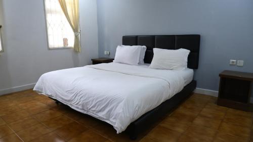 Un dormitorio con una cama grande con sábanas y almohadas blancas. en Diyar Villas Puncak Q4/11, en Puncak