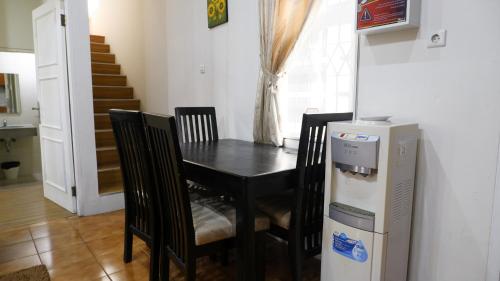 a black dining room table with chairs and a refrigerator at Diyar Villas Puncak Q4/11 in Puncak