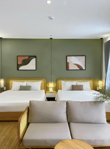 a hotel room with two beds and a couch at Triland Hotel in Phú Quốc