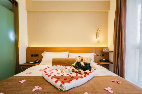 a teddy bear sitting on a bed with a heart at James Joyce Coffetel Chengdu Jichang Road Shenxianshu in Chengdu