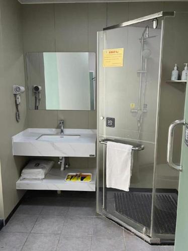 a bathroom with a sink and a shower with a mirror at 7 Days Inn Xingyi Wanfenglin Xiawutun in Xiawutun