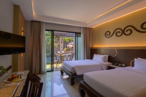 a hotel room with two beds and a balcony at Le Bali Resort in North Pattaya