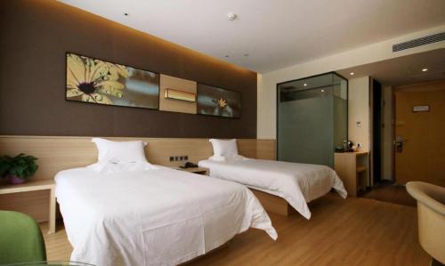 a hotel room with two beds with white sheets at IU Hotel Zhangye High-Speed Railway Station in Zhangye