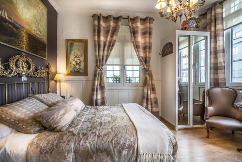 a bedroom with a bed and a chair and a chandelier at Hotel Boutique Las Brisas in Santander