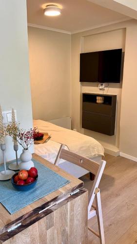 a living room with a table and a television on a wall at Nyoppusset studio nær Horten sentrum in Nykirke