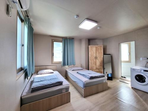 a bedroom with two beds and a washing machine at Wandonesia in Wando