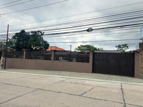 ein Haus mit einem Zaun und einem Tor mit Stromleitungen in der Unterkunft Gran Hostal Sula in San Pedro Sula