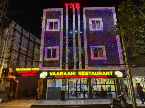 a building with a lit up sign in front of it at Vaaraahi Hotels in Hyderabad