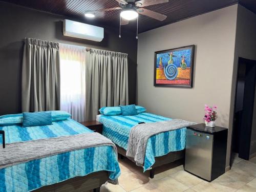 ein Schlafzimmer mit zwei Betten und einem Deckenventilator in der Unterkunft Gran Hostal Sula in San Pedro Sula