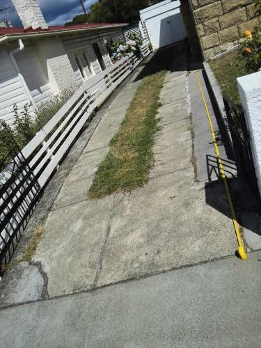 a driveway with a white fence and a yellow pole at Rocklyn House in Moonah