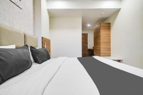 a bedroom with a large white bed with black pillows at Super Townhouse Oak PTC Indore Junction in Indore