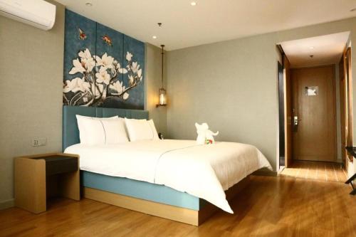 a bedroom with a large bed with a painting on the wall at Magnotel Hengshui Lake Jizhou Middle School in Hengshui