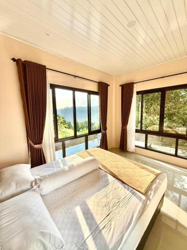 Un dormitorio con una cama grande con grandes ventanales. en Villa Marlinda, en Narmada