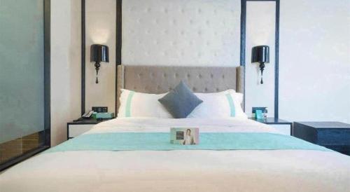 a bedroom with a bed with a book on it at Xana Hotelle Jinan Wuanfu Interchange Huafu International Square in Jinan