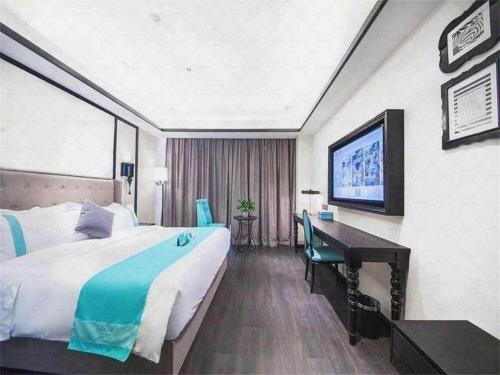 a hotel room with a large bed and a desk at Xana Hotelle Jinan Wuanfu Interchange Huafu International Square in Jinan