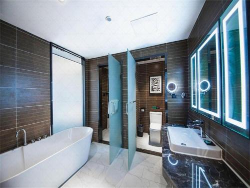 a bathroom with a tub and a sink at Xana Hotelle Jinan Wuanfu Interchange Huafu International Square in Jinan
