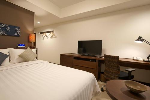 a bedroom with a bed and a desk with a television at Axia South Cikarang Service Apartment in Cikarang