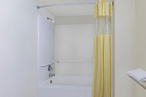a shower with a yellow shower curtain in a bathroom at Days Inn Windcrest by Wyndham San Antonio in San Antonio