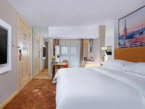 a hotel room with a large white bed and a television at Vienna Hotel Chengdu Exhibition Center In Time City in Chengdu
