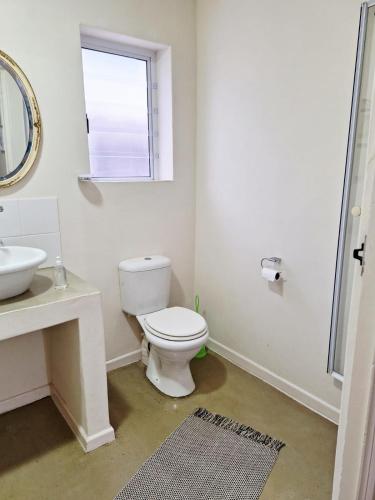 a bathroom with a toilet and a sink and a window at Tweede Lente in St Helena Bay