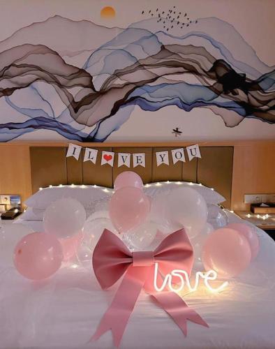 a bed with balloons and a sign that says love at Venus Royal Hotel Nanning East High-Speed Railway Station in Nanning