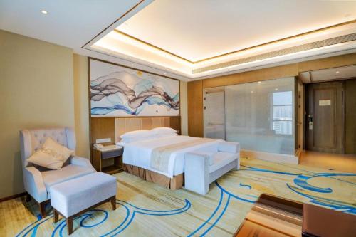 a large bedroom with a large bed and a chair at Venus Royal Hotel Nanning East High-Speed Railway Station in Nanning