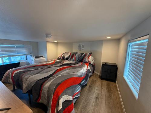 a bedroom with a bed with a striped comforter and a window at Park Model Home 268 at Silverview RV Resort in Bullhead City