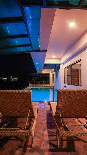 a swimming pool with two wicker chairs and a swimming pool at The Misty Villas Igatpuri by Natura Stays, 6 BHK in Igatpuri