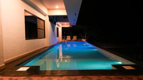 a swimming pool in the middle of a building at night at The Misty Villas Igatpuri by Natura Stays, 6 BHK in Igatpuri
