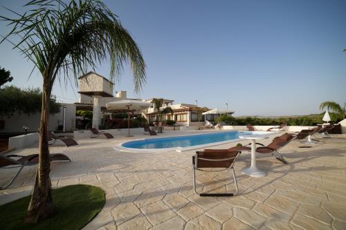 a pool with chairs and a palm tree next to a building at Le Zarafe in Caltabellotta