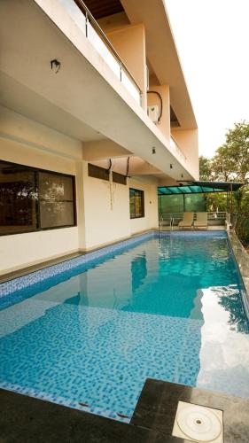 a swimming pool with blue water in a building at The Misty Villas Igatpuri by Natura Stays, 6 BHK in Igatpuri