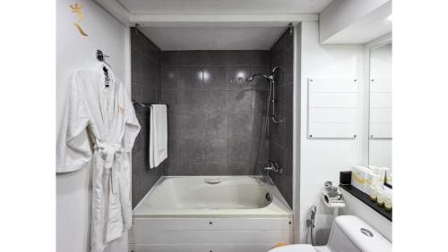 a white bathroom with a tub and a sink at Modern 1BR - Poolside & Gym Escape in Abu Dhabi