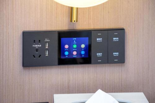 a tv on a wall with a remote control at Lavande Hotel Guangzhou Quzhuang Metro Station in Guangzhou