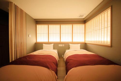 two beds in a small room with windows at Hakone Fuga - Adult Only in Hakone