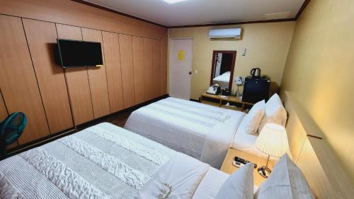 a hotel room with two beds and a television at Kyungha Spa Hotel in Daejeon