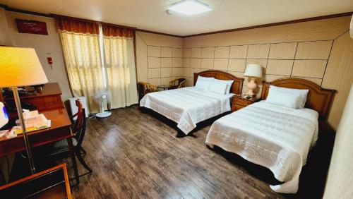 a hotel room with two beds and a desk at Kyungha Spa Hotel in Daejeon