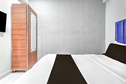 a bedroom with a white bed and a wooden door at Super Hotel O Sneh Rashmi Botanical Garden Surat Formerly Stadium Plaza in Bhatha