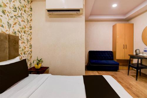 a hotel room with a bed and a blue chair at Super Townhouse Parkstreet Formerly Hotel Royal Garden in Ballygunge