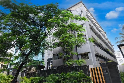 a white building with trees in front of it at Super Townhouse Parkstreet Formerly Hotel Royal Garden in Ballygunge