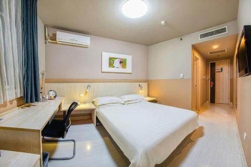 a bedroom with a large white bed and a desk and a computer at Jinjiang Inn Baotou Donghe East Railway Station in Baotou