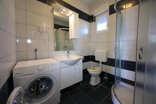 a bathroom with a washing machine and a sink at Apartments Šuperba in Brodarica