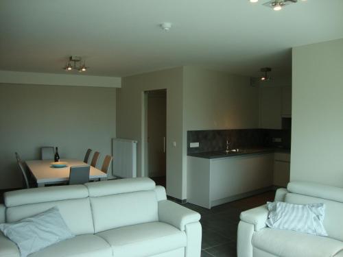 ein Wohnzimmer mit einem weißen Sofa und einer Küche in der Unterkunft Karthuizer Zeezicht I in Nieuwpoort