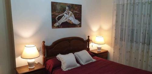 a bedroom with a red bed with two lamps at Piso de Perlío, ideal para gente amante de la pla in Fene