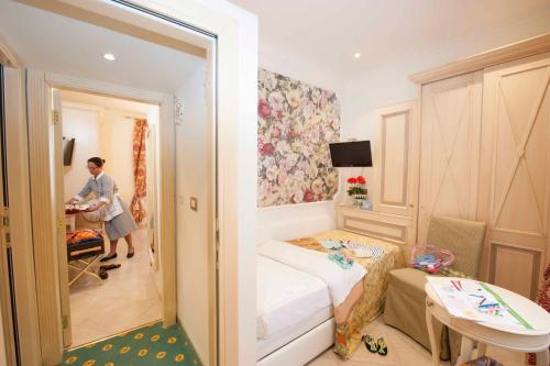 a woman standing in a small room with a bedroom at Hotel Astigiana & Appartamenti in Varazze