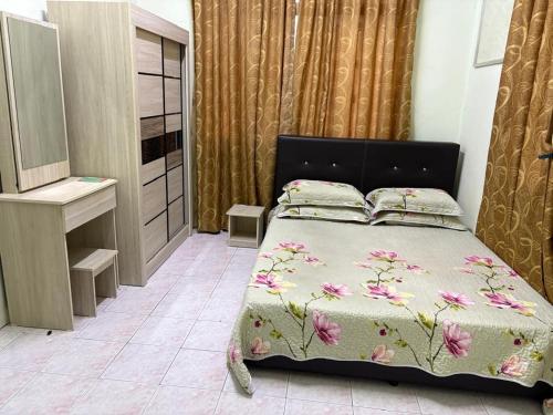 a bedroom with a bed with a bedspread with flowers at Sofya Homestay Kangar in Kangar