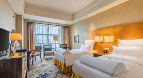 a hotel room with two beds and a television at Kunshan Newport Hotel in Suzhou