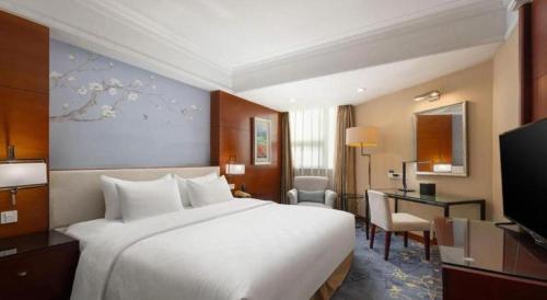 a hotel room with a large bed and a desk at Linyi Blue Horizon Intenational Hotel in Linyi