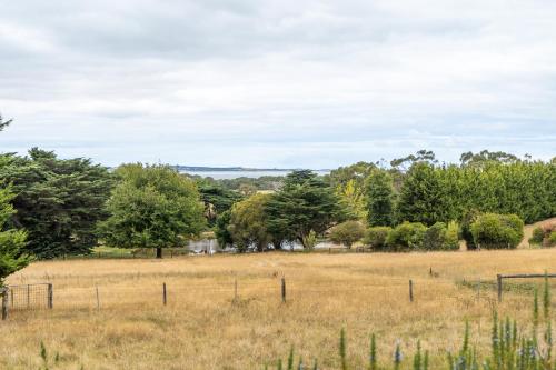 a field with a fence and trees in the background at Country Home Stay, Animals, 2 Properties Sleeps 15 in Balnarring